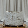 Large stone planter on a wooden pallet with a gray curtain background