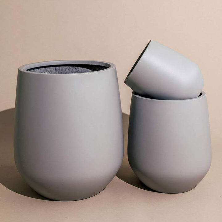 Three sizes of mud Lucy Pots with the smallest one tilted on its side on top of the medium size.